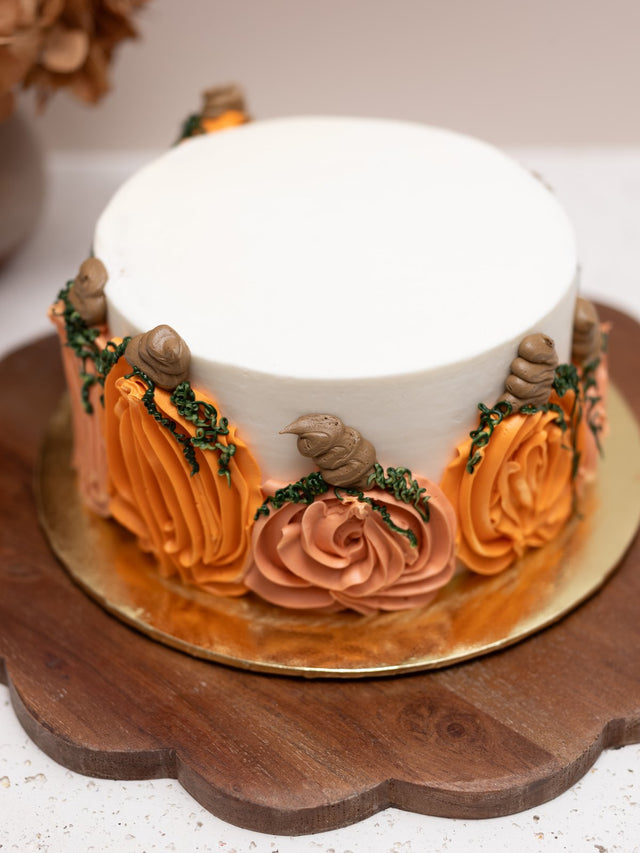 White cake with piped orange pumpkins around the side
