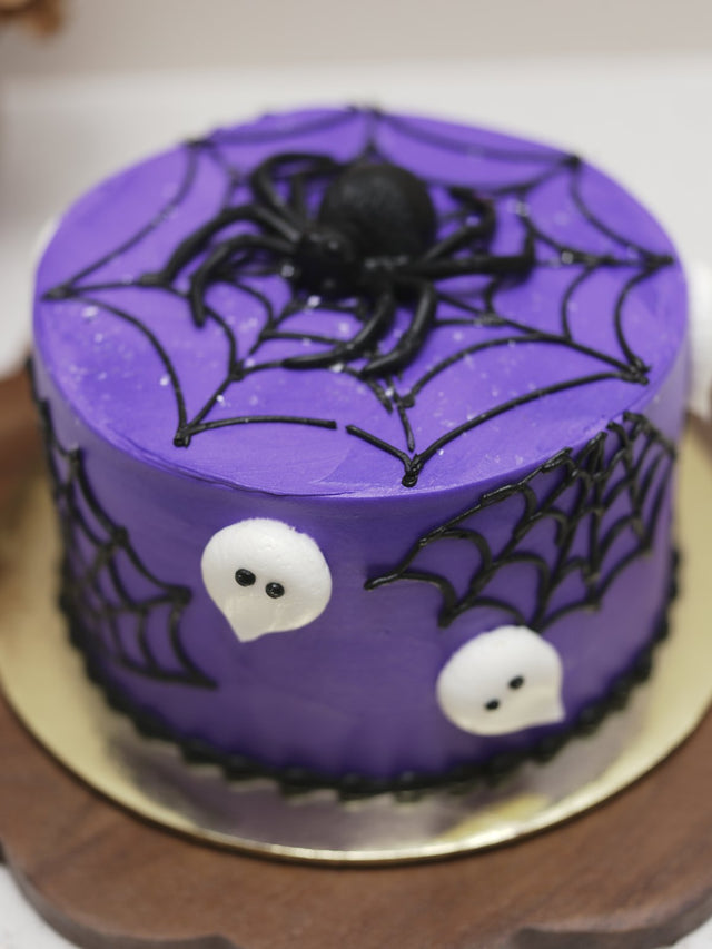 Purple Halloween cake with spider webs, a spider, and ghosts