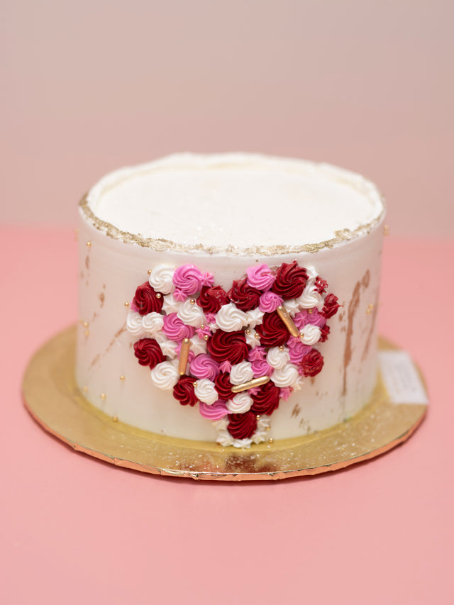 Decorative cake with heart-shaped floral design on a pink background
