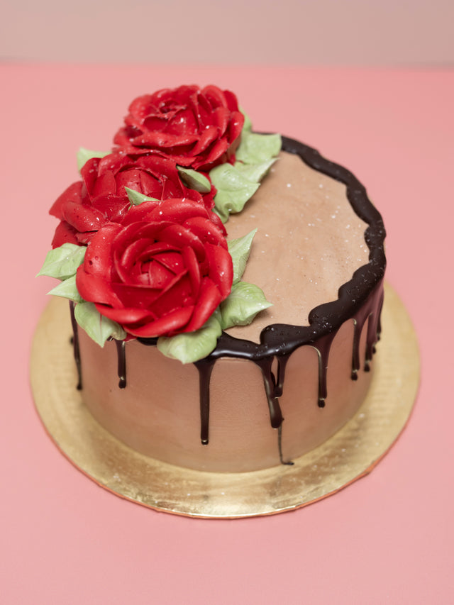 Chocolate cake with red roses on a pink background
