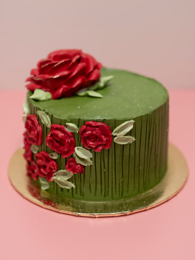 Green cake with red roses on a pink surface